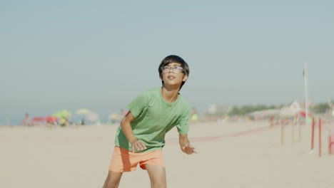 Slow-motion-of-kid-kicking-ball-in-jump-and-falling-on-sand